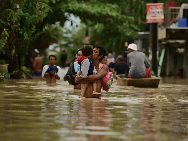 Mehrere Menschen in einer überschwemmten Gegend auf den Philippinen.