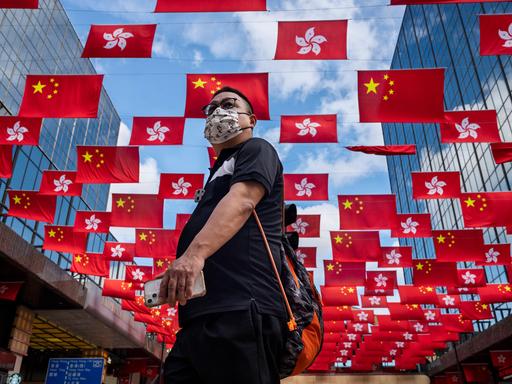 Ein Passant vor chinesischen Flaggen als Fähnchen in einer Straße in Hongkong