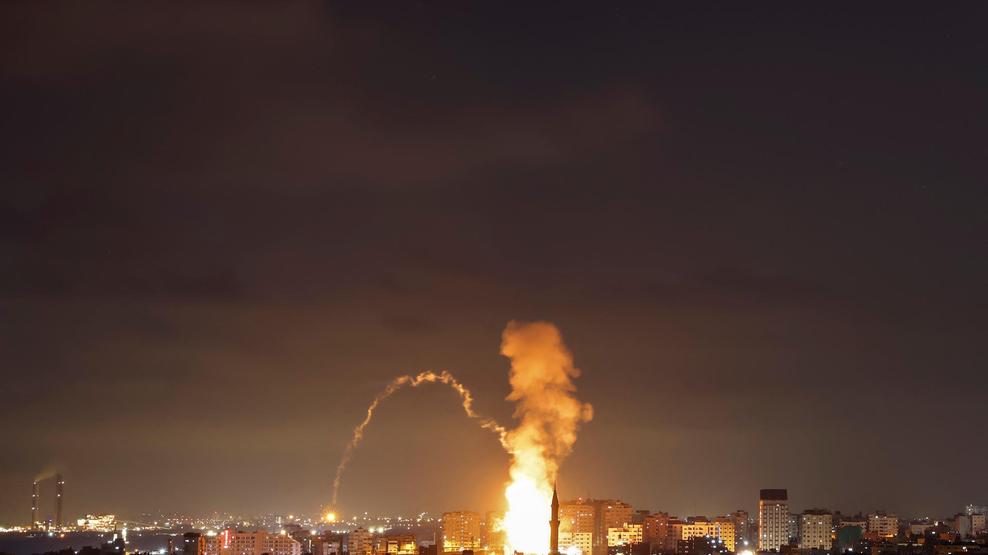 Es ist Nacht; das Bild ist aus großer Ferne aufgenommen. Über Gazastadt sind ein Feuerball und Rauchwolken zu sehen.