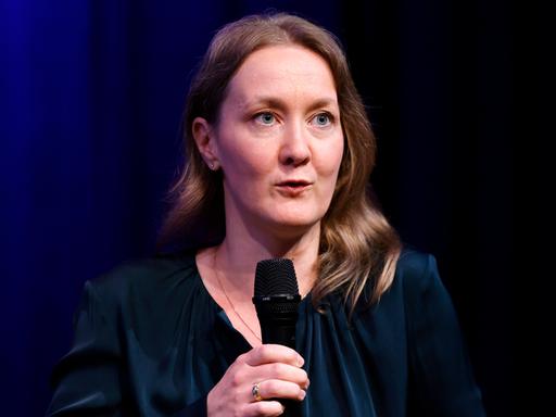 Rechtsphilosophin Frauke Rostalski auf der Phil.Cologne 2024. Rostalski hat schulterlange, dunkle Haare und trägt ein dunkles Oberteil. Sie hält ein Mikro in der Hand.