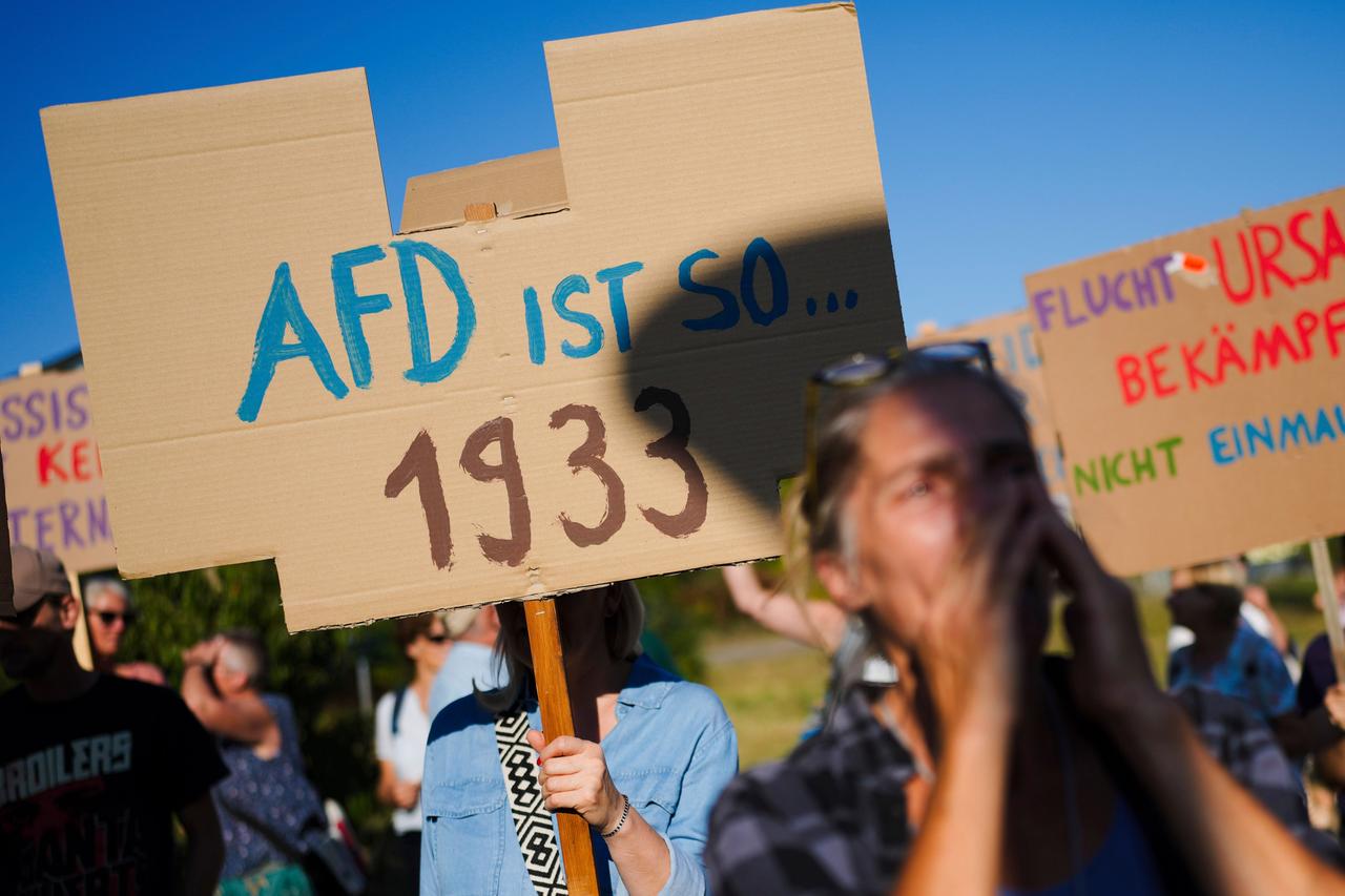 Demonstranten halten Plakate mit Aufschriften in die Höhe.