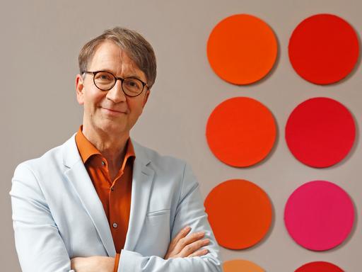 Axel Buether posiert vor einer Wand mit farbigen Kreisen für ein Pressefoto. Axel Buether posiert vor einer Wand mit farbigen Kreisen für ein Pressefoto.