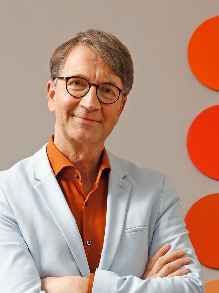 Axel Buether posiert vor einer Wand mit farbigen Kreisen für ein Pressefoto. Axel Buether posiert vor einer Wand mit farbigen Kreisen für ein Pressefoto.