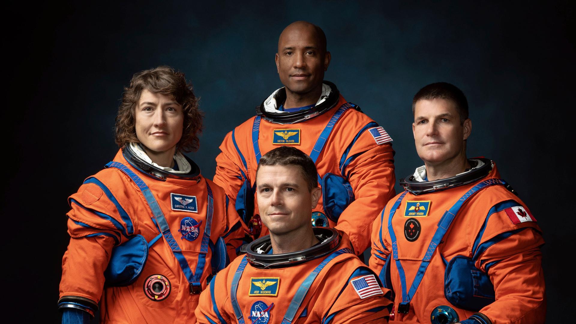 Das Foto zeigt die Crew der Mondmission "Artemis II" in orangefarbenen Raumanzügen.