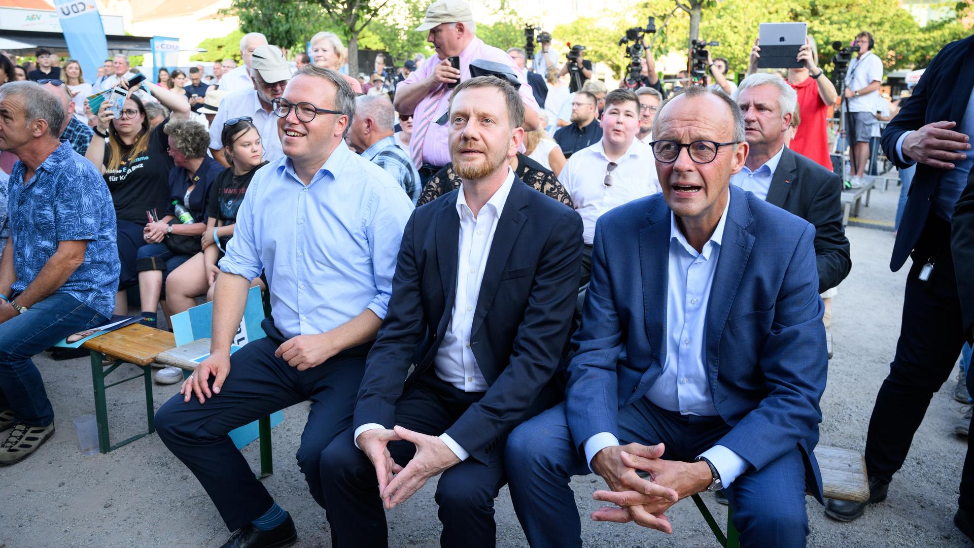 CDU-Chef Friedrich Merz (r), Sachsens MInisterpräsident Michael Kretschmer und Mario Voigt (l), Spitzenkandidat und Landesvorsitzender der CDU Thüringen, sitzen im Brandenburger Wahlkampf auf dem Neustädtischen Markt in Brandenburg an der Havel. 