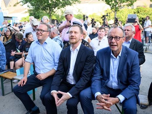 CDU-Chef Friedrich Merz (r), Sachsens MInisterpräsident Michael Kretschmer und Mario Voigt (l), Spitzenkandidat und Landesvorsitzender der CDU Thüringen, sitzen im Brandenburger Wahlkampf auf dem Neustädtischen Markt in Brandenburg an der Havel. 