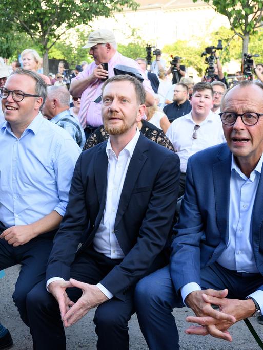 CDU-Chef Friedrich Merz (r), Sachsens MInisterpräsident Michael Kretschmer und Mario Voigt (l), Spitzenkandidat und Landesvorsitzender der CDU Thüringen, sitzen im Brandenburger Wahlkampf auf dem Neustädtischen Markt in Brandenburg an der Havel. 