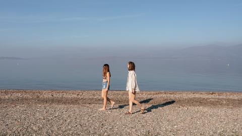 Zwei junge Frauen laufen an einem leeren Strand der griechischen Insel Lesbos Zwei junge Frauen laufen an einem leeren Strand der griechischen Insel Lesbos