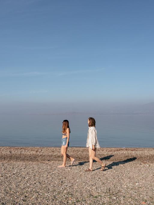 Zwei junge Frauen laufen an einem leeren Strand der griechischen Insel Lesbos