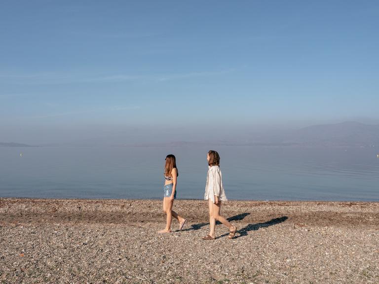 Zwei junge Frauen laufen an einem leeren Strand der griechischen Insel Lesbos