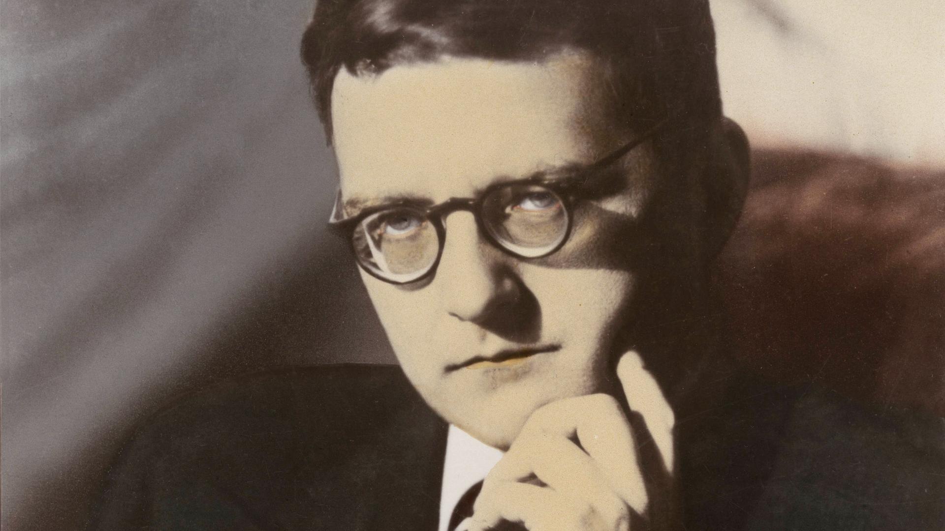 Dimitrij Schostakowitsch sitzt auf einer Fotografie von 1940 ernst schauend vor der Kamera und stützt sein Kinn in seine linke Hand.