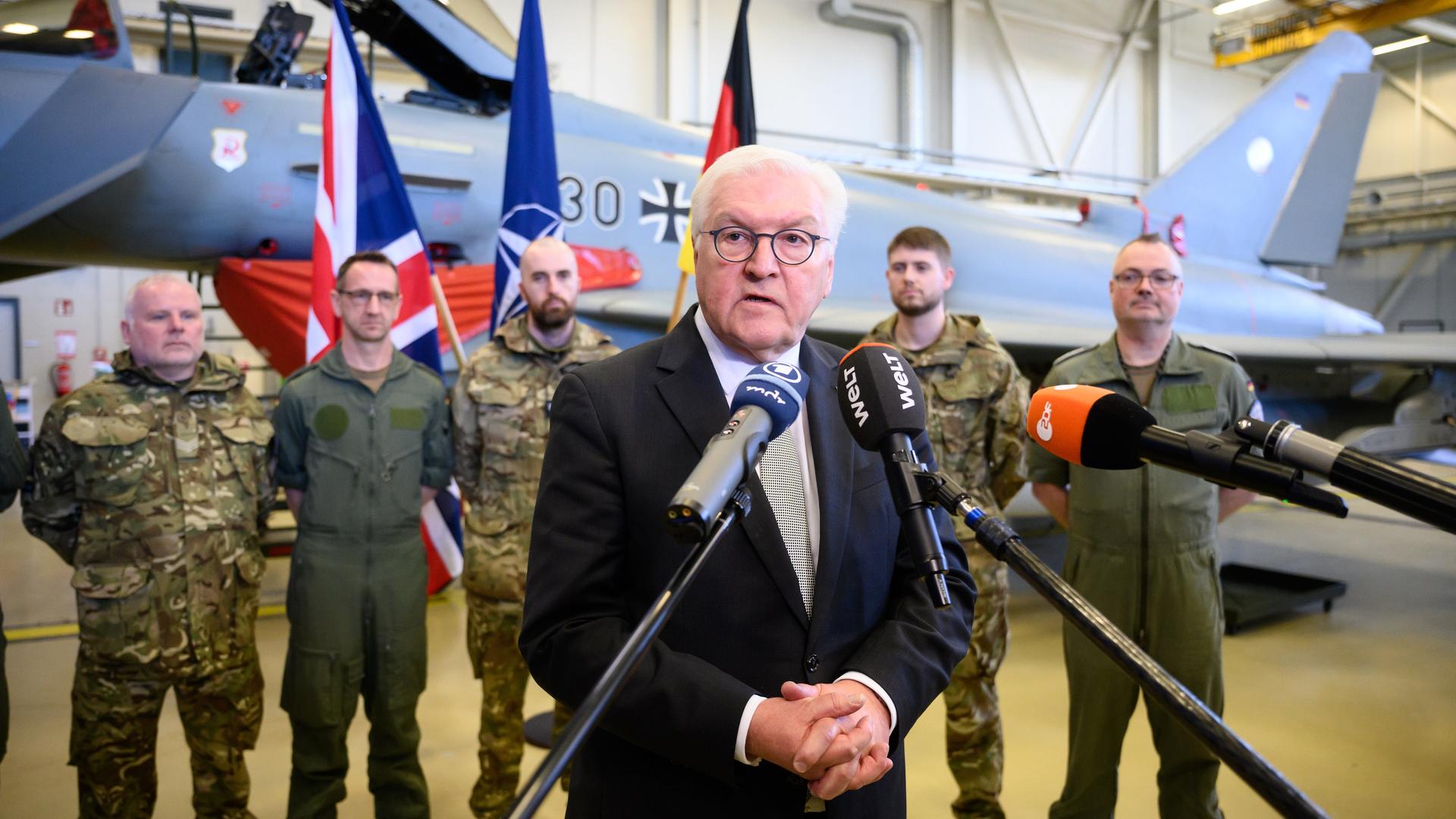 Bundespräsident Frank-Walter Steinmeier spricht auf der estnischen Luftwaffenbasis Ãmari in mehrere Mikrofone. Hinter ihn stehen deutsche und britische Soldatinnen und Soldaten vor einem dort stationierten Eurofighter. Bundespräsident Frank-Walter Steinmeier spricht auf der estnischen Luftwaffenbasis Ãmari in mehrere Mikrofone. Hinter ihn stehen deutsche und britische Soldatinnen und Soldaten vor einem dort stationierten Eurofighter.