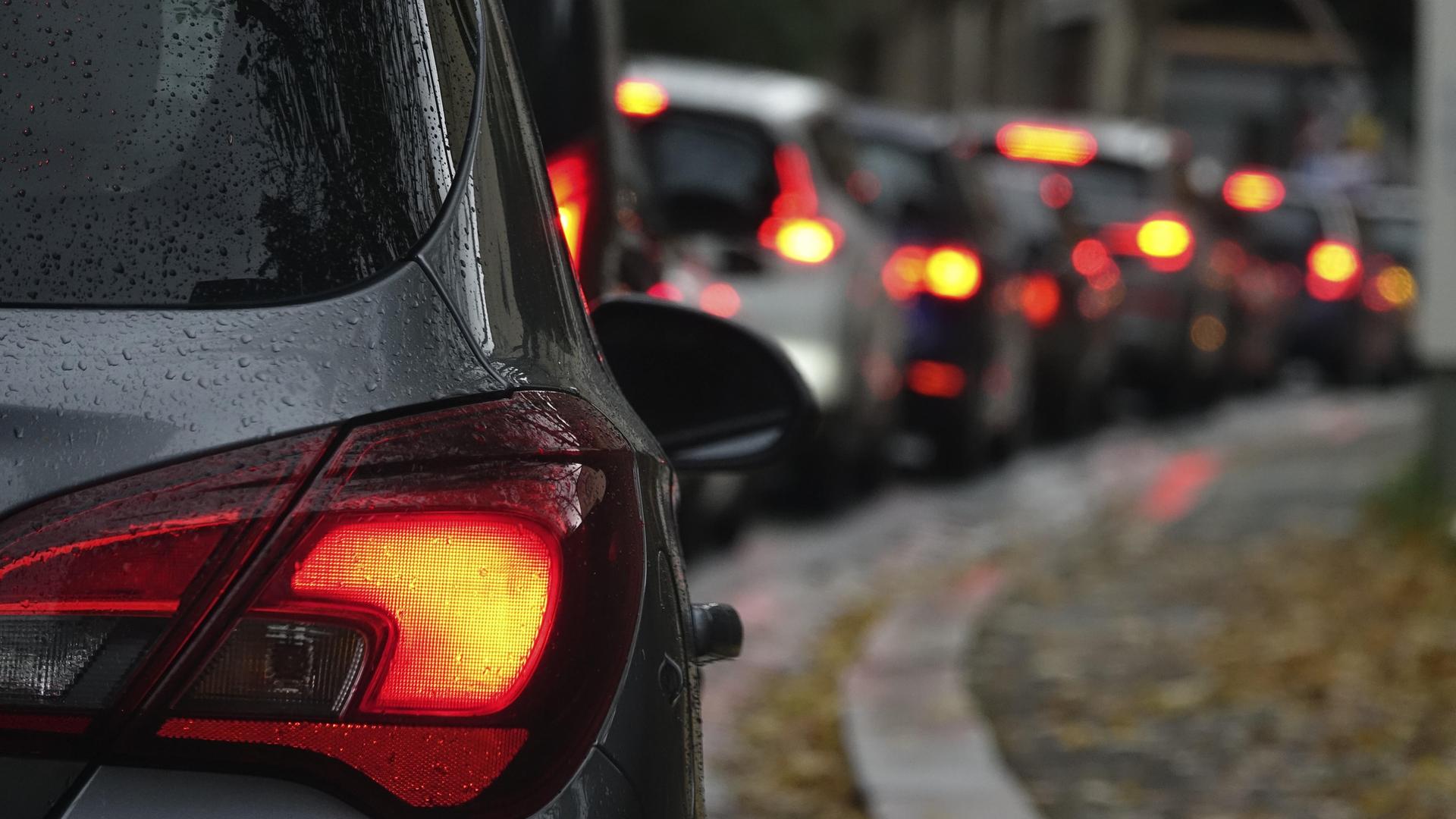Autos stehen im Straßenverkehr im Stau. Die roten Rücklichter leuchten.
