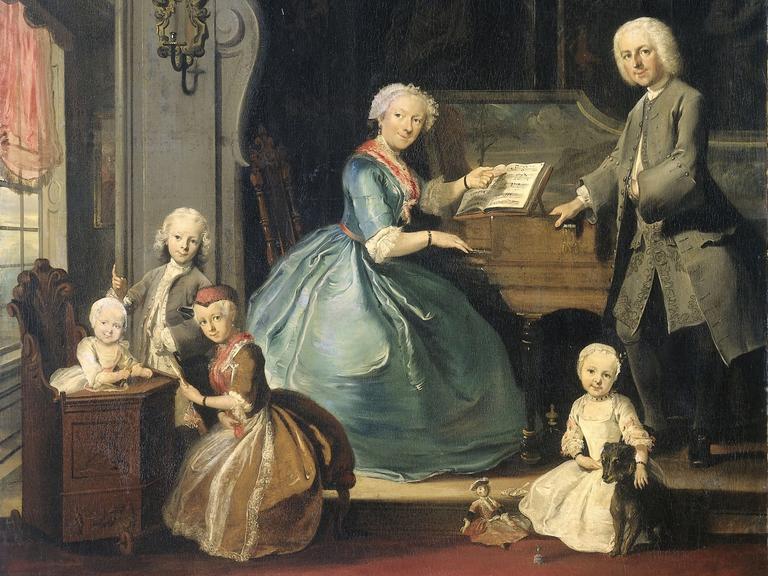 Auf einem Gemälde aus der Barockzeit, das Cornelis Troost zugeschrieben wird (1739) sitzt ein Frau mit heller Haube am Cembalo, während sie von ihrer Familie umringt ist.