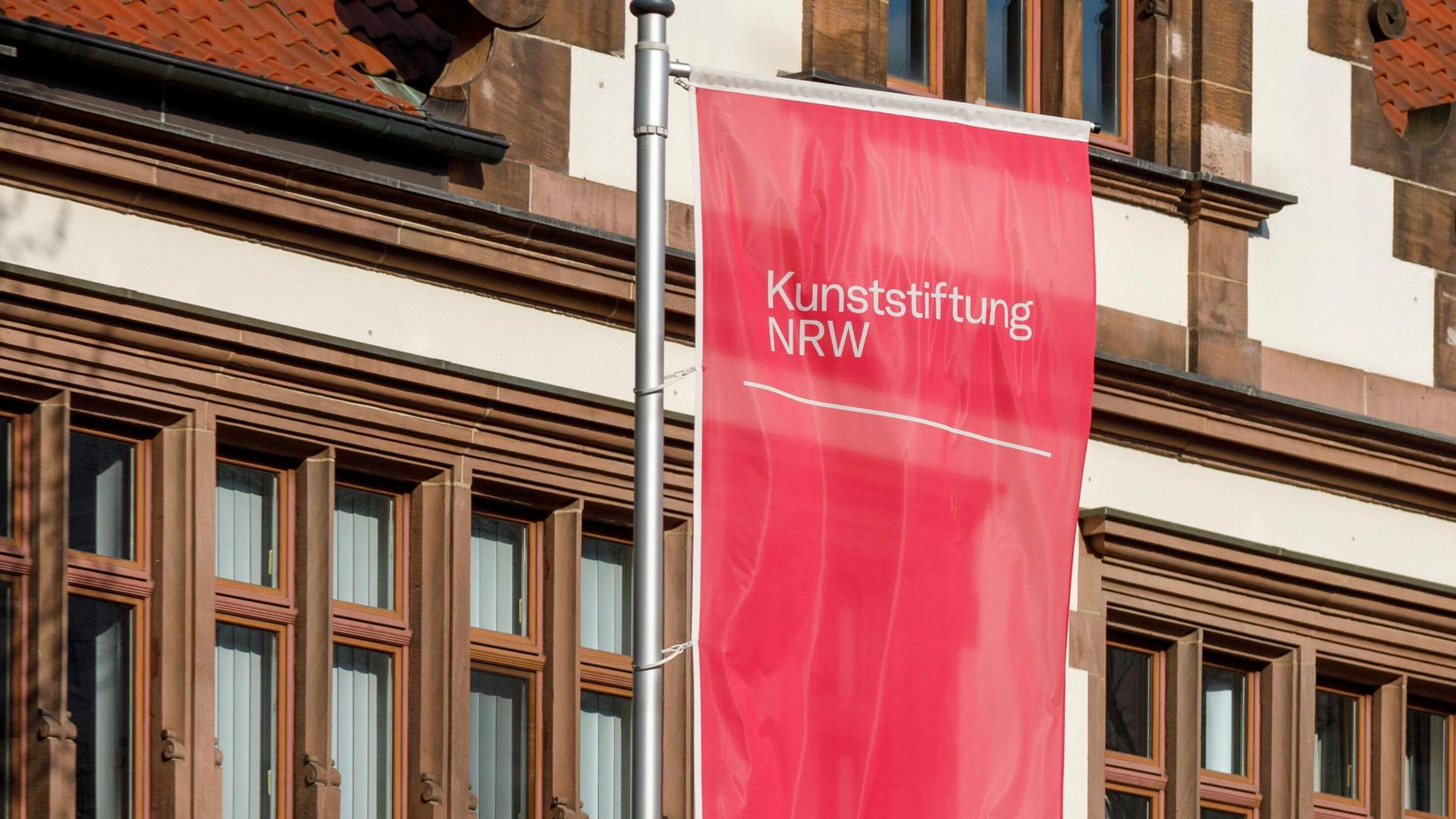 Eine rote Fahne mit der Aufschrift "Kunststiftung NRW"
Eine rote Fahne mit der Aufschrift "Kunststiftung NRW"