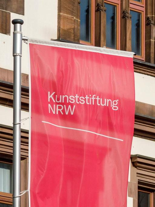Eine rote Fahne mit der Aufschrift "Kunststiftung NRW"
      