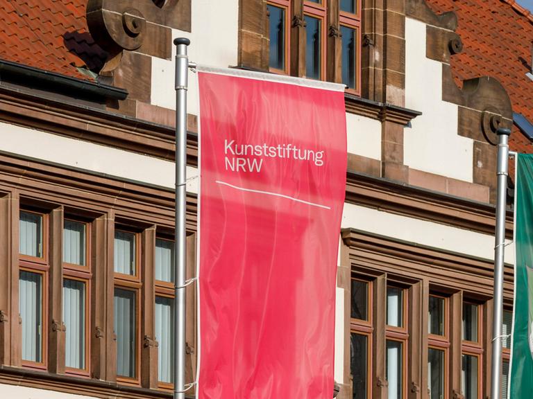 Eine rote Fahne mit der Aufschrift "Kunststiftung NRW"
      