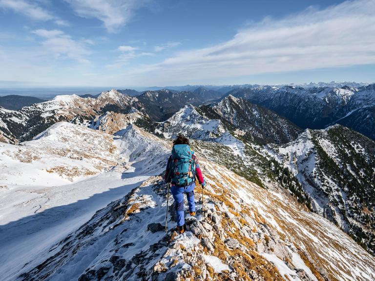 Bergsteigerin am schmalen felsigen verschneiten Grat der Ammergauer Hochplatte, Blick Richtung Lösertaljoch, Ausblick auf Bergpanorama