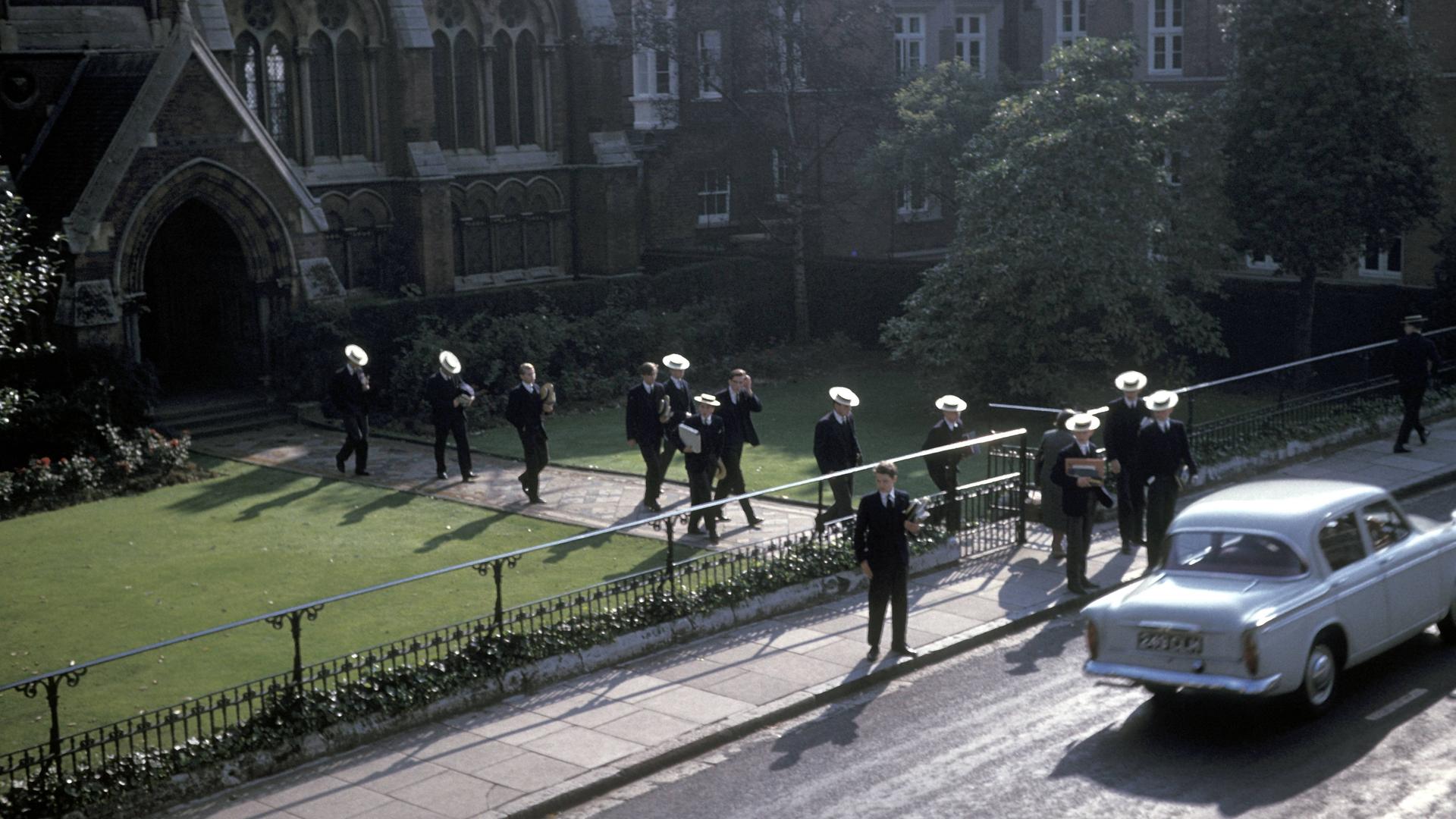 Schuljungen gehen vom Eingang  der Harrow School in England richtung Straße.