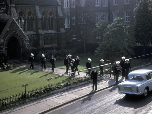 Schuljungen gehen vom Eingang  der Harrow School in England richtung Straße.