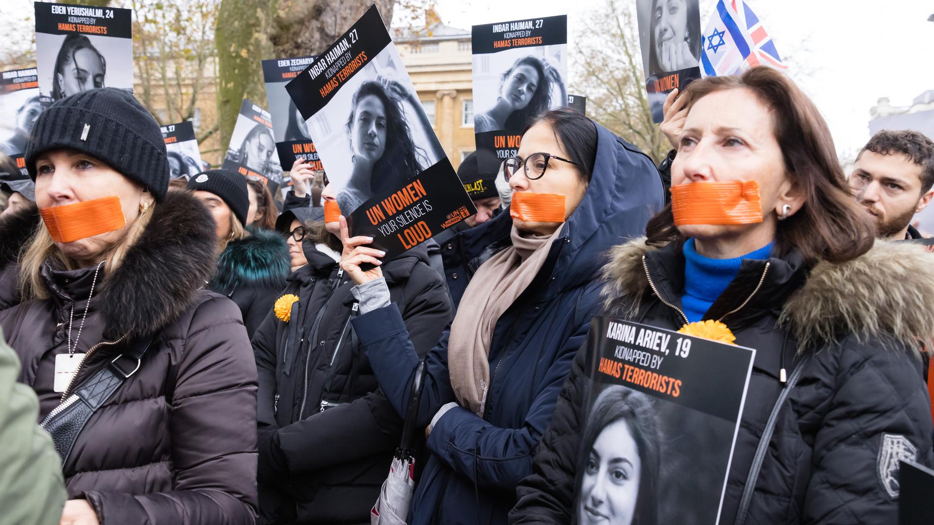 Bei einer Demonstration in London haben sich Teilnehmende den Mund zugeklebt und halten Schilder hoch.
