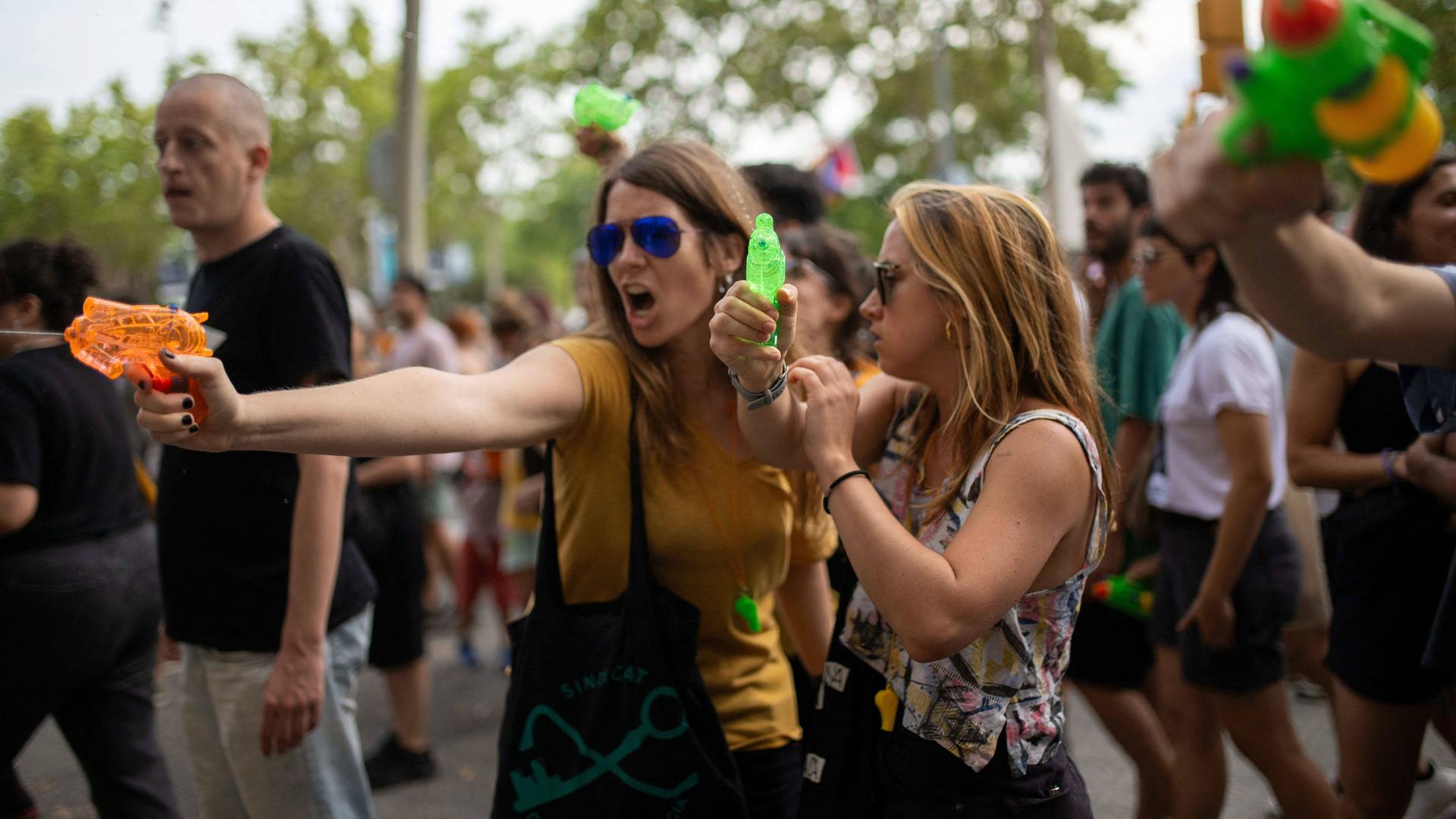 Zwei Frauen schießen mit Wasserspritzpistolen bei einer Demonstration gegen den Massentourismus am 6. Juli 2024 in Barcelona, Katalonien, Spanien. Rund 2.800 Menschen haben nach Angaben der Stadtverwaltung unter dem Motto "Genug" im Zentrum von Barcelona gegen den Massentourismus demonstriert. 