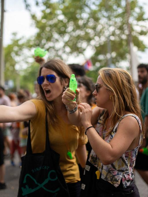 Zwei Frauen schießen mit Wasserspritzpistolen bei einer Demonstration gegen den Massentourismus am 6. Juli 2024 in Barcelona, Katalonien, Spanien. Rund 2.800 Menschen haben nach Angaben der Stadtverwaltung unter dem Motto "Genug" im Zentrum von Barcelona gegen den Massentourismus demonstriert. 
