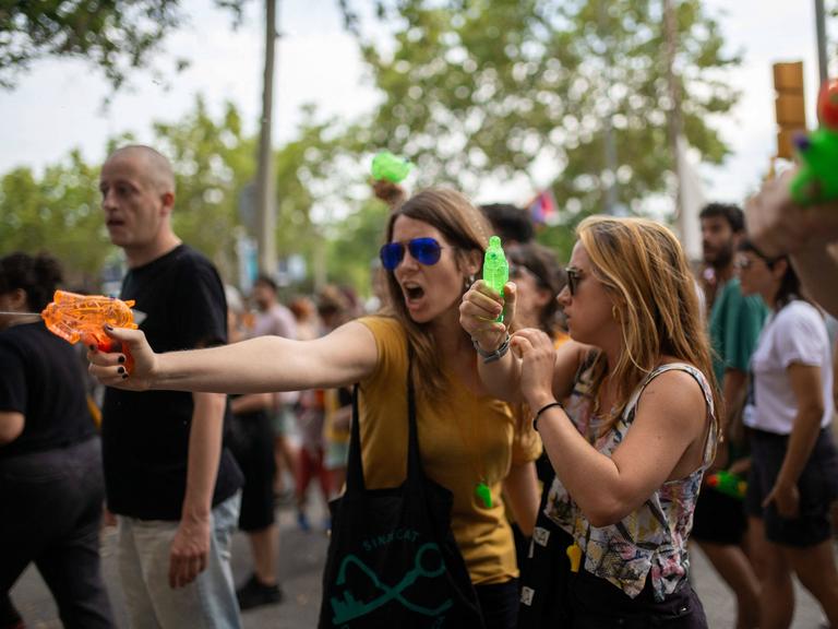 Zwei Frauen schießen mit Wasserspritzpistolen bei einer Demonstration gegen den Massentourismus am 6. Juli 2024 in Barcelona, Katalonien, Spanien. Rund 2.800 Menschen haben nach Angaben der Stadtverwaltung unter dem Motto "Genug" im Zentrum von Barcelona gegen den Massentourismus demonstriert. 