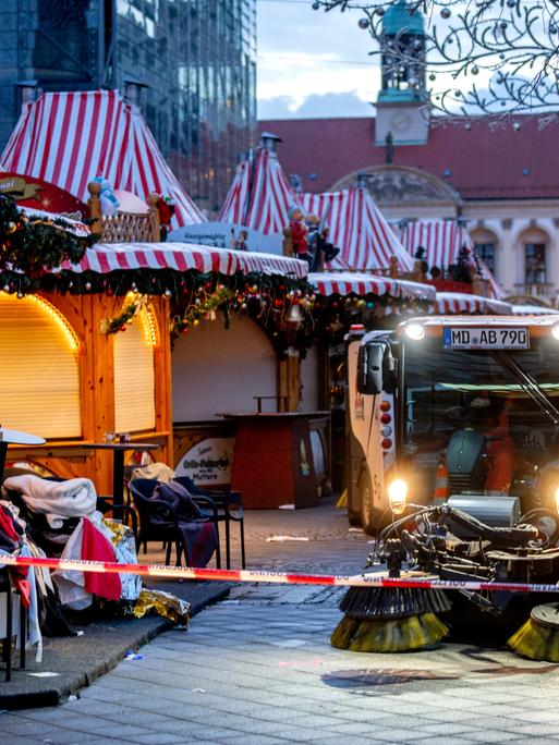 Der Magdeburger Weihnachtsmakrt mit geschlossenen Ständen. Ein Reingungsfahrzeug putzt davor die Straße. Im Hintergrund zeichnen sich Teile der Johanniskirche ab.