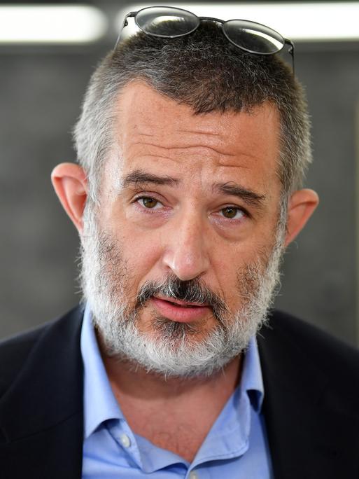 Portrait von Stephan Kramer, der seine Brille auf den Kopf gerückt hat und in die Kamera spricht