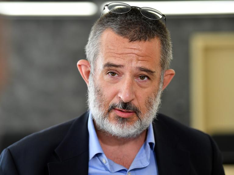 Portrait von Stephan Kramer, der seine Brille auf den Kopf gerückt hat und in die Kamera spricht