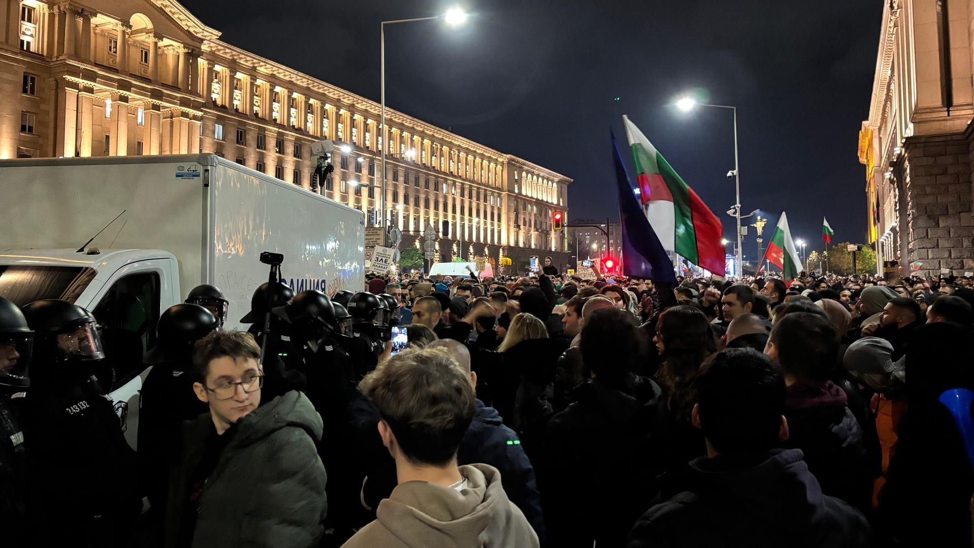Tausende Menschen stehen am Independence Platz in Sofia, einige halten Fahnen hoch. Tausende Menschen stehen am Independence Platz in Sofia, einige halten Fahnen hoch.