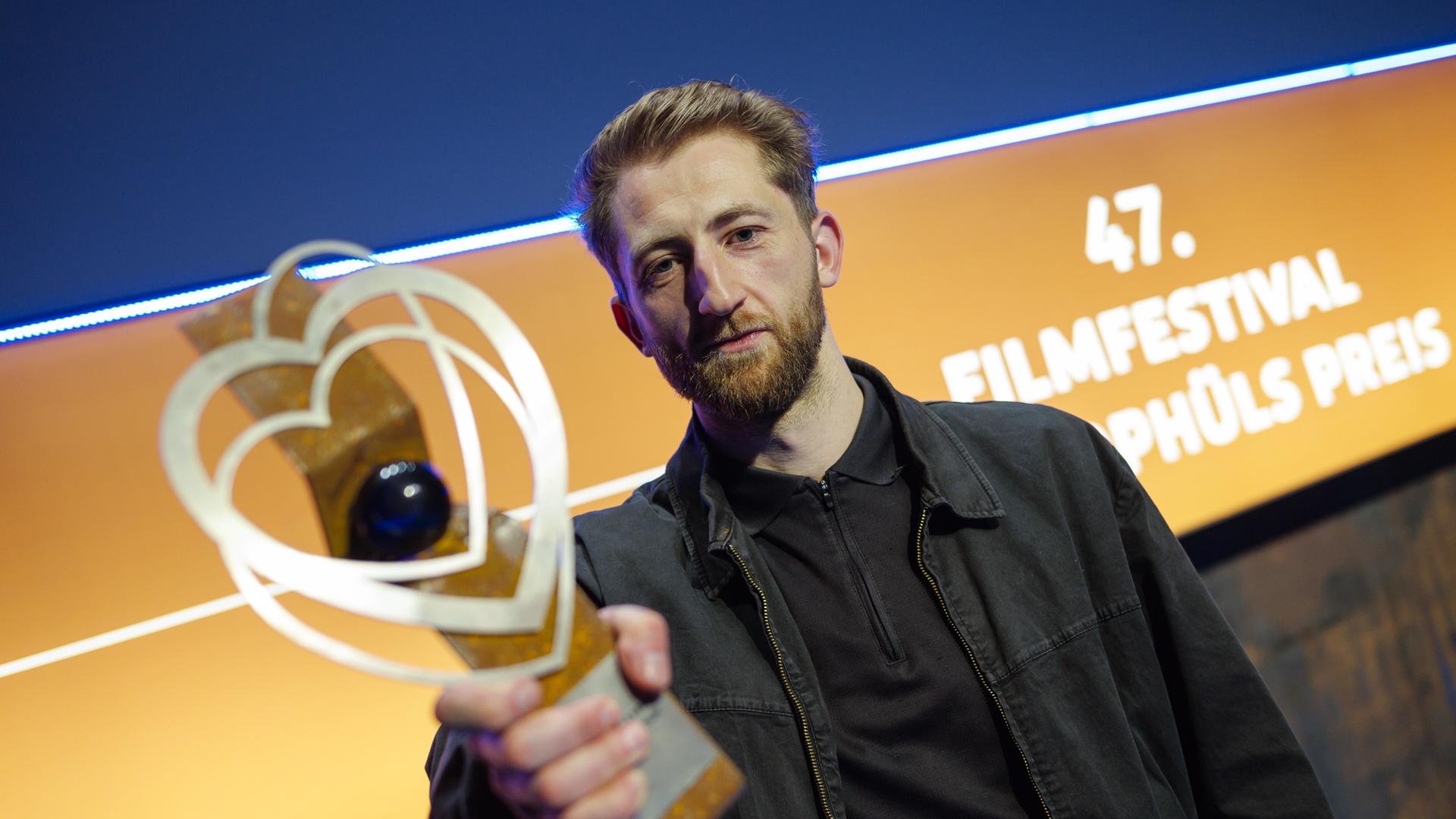 Ben Voit hält einen Pokal in die Kamera, im Hintergrund ist zu lesen: "47. Filmfestival"