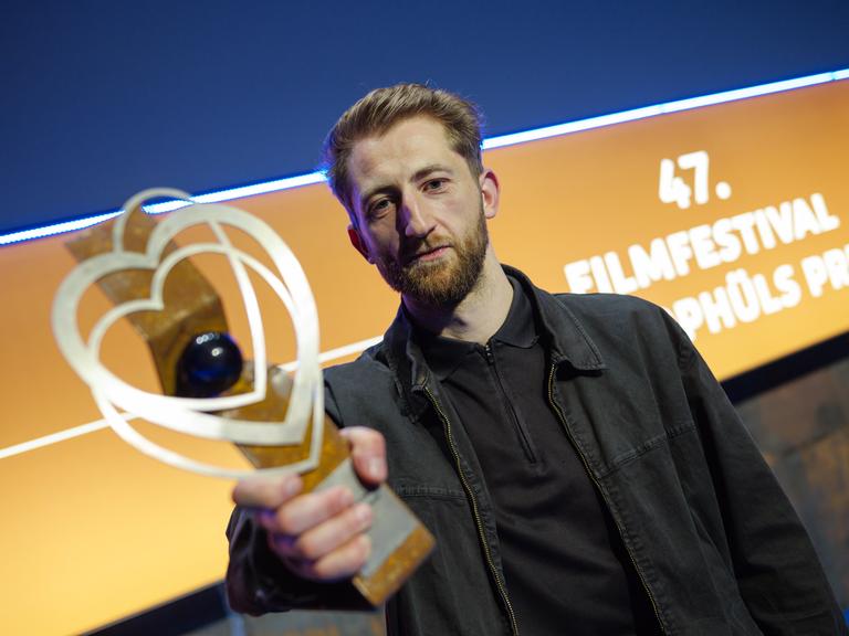 Ben Voit hält einen Pokal in die Kamera, im Hintergrund ist zu lesen: "47. Filmfestival"