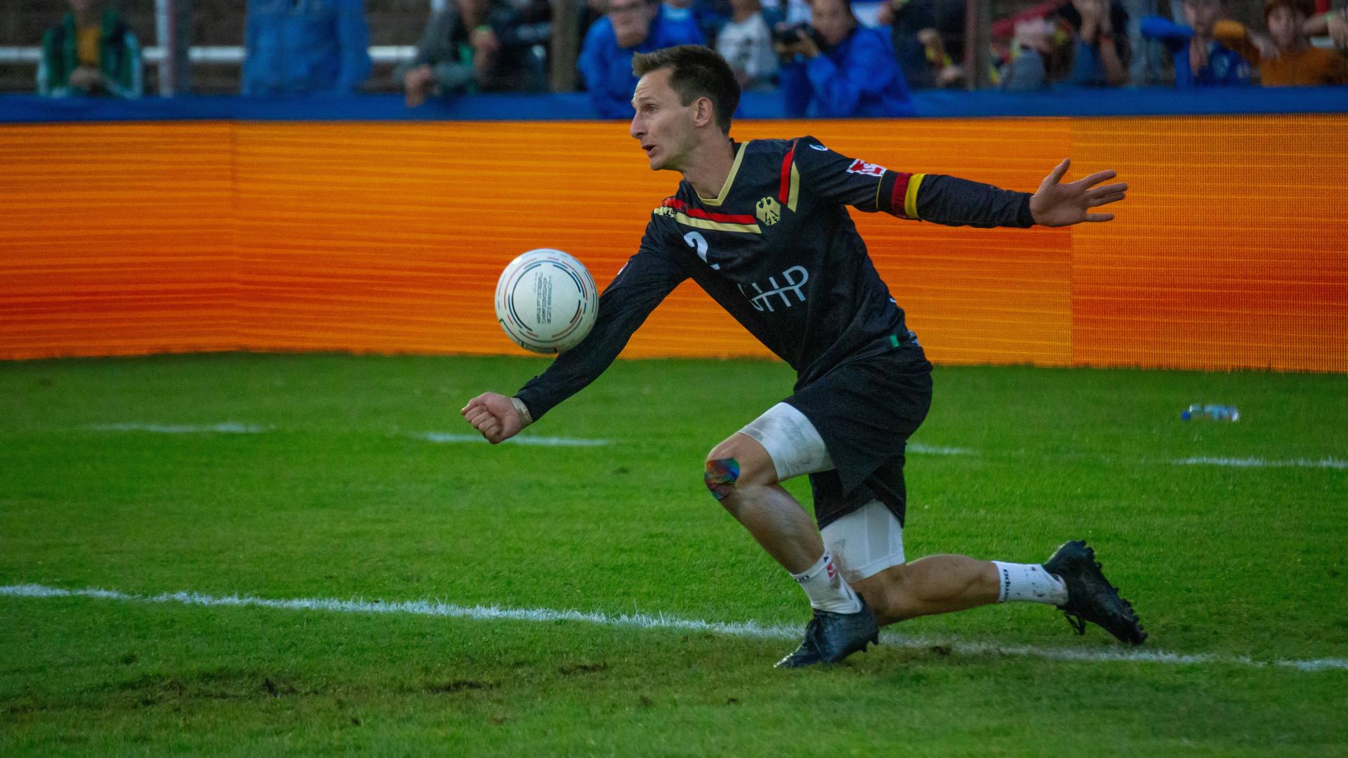 Ein deutscher Faustballspieler schlägt den Ball mit dem Unterarm.