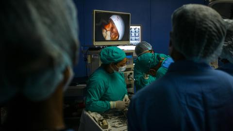 Ein Team aus Ärztinnen und Ärzten behandelt einen Patienten mit Mukormykose-Infektion während der Coronapandemie. Auf einem Bildschirm im Hintergrund ist das Gesicht des Patienten zu sehen. Ein Team aus Ärztinnen und Ärzten behandelt einen Patienten mit Mukormykose-Infektion während der Coronapandemie. Auf einem Bildschirm im Hintergrund ist das Gesicht des Patienten zu sehen.