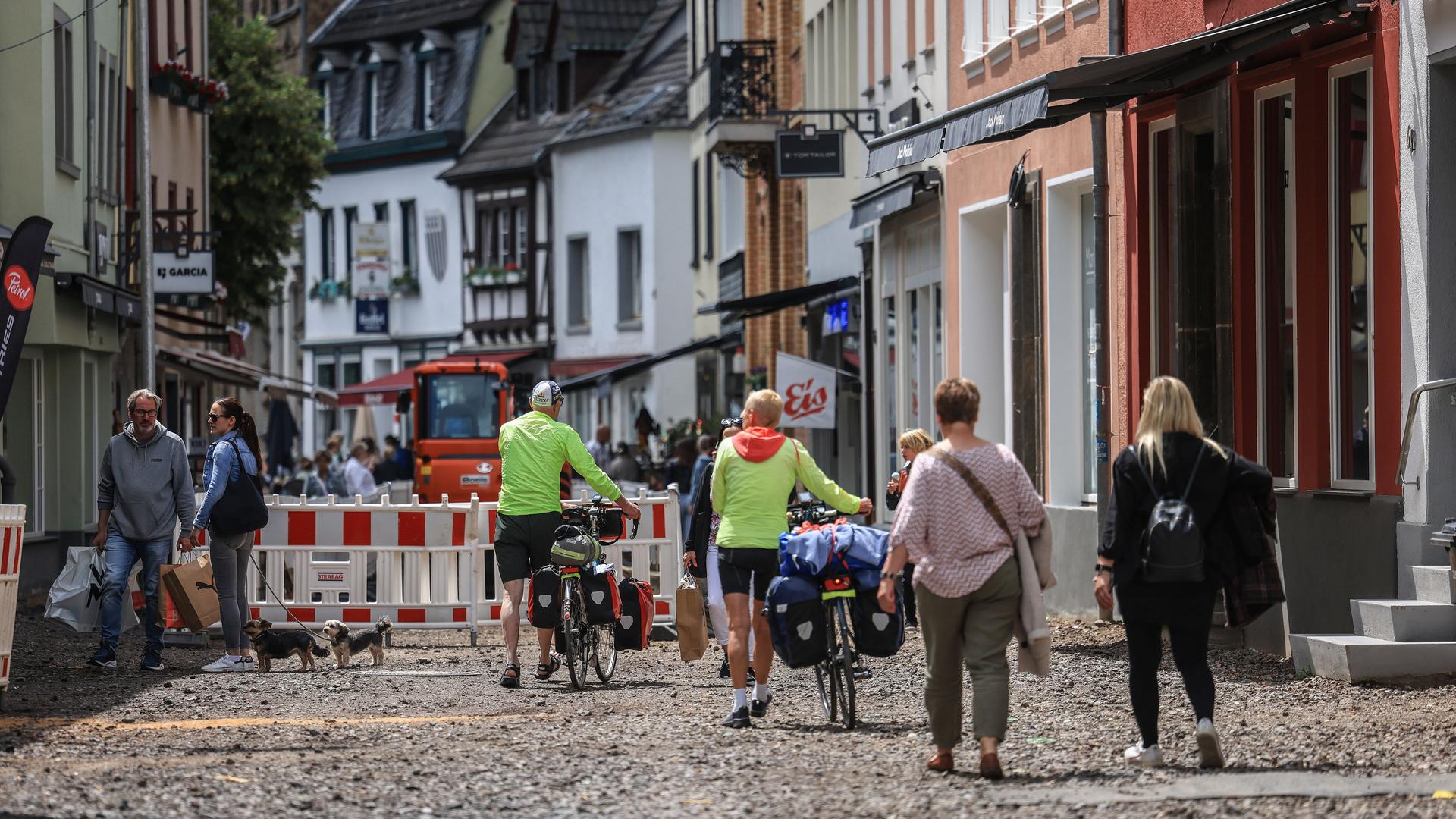 Menschen gehen durch einen Teil der Fußgängerzone von Münstereifel, die immer noch wiederaufgebaut wird. 