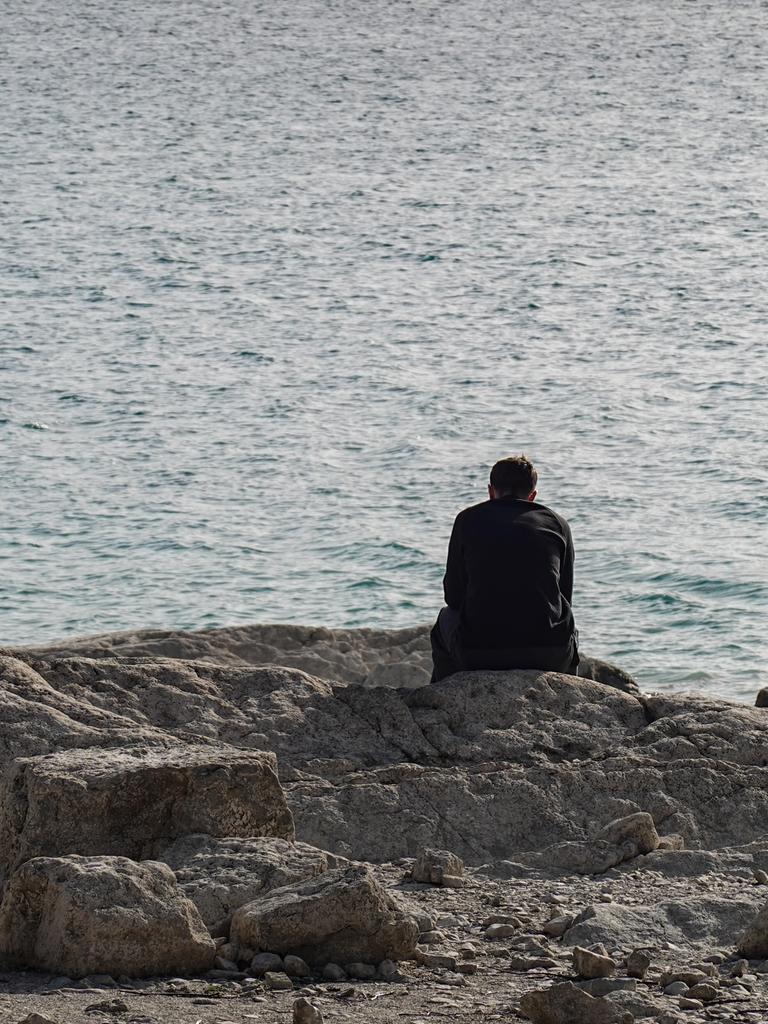 Ein Mann sitzt allein am Seeufer