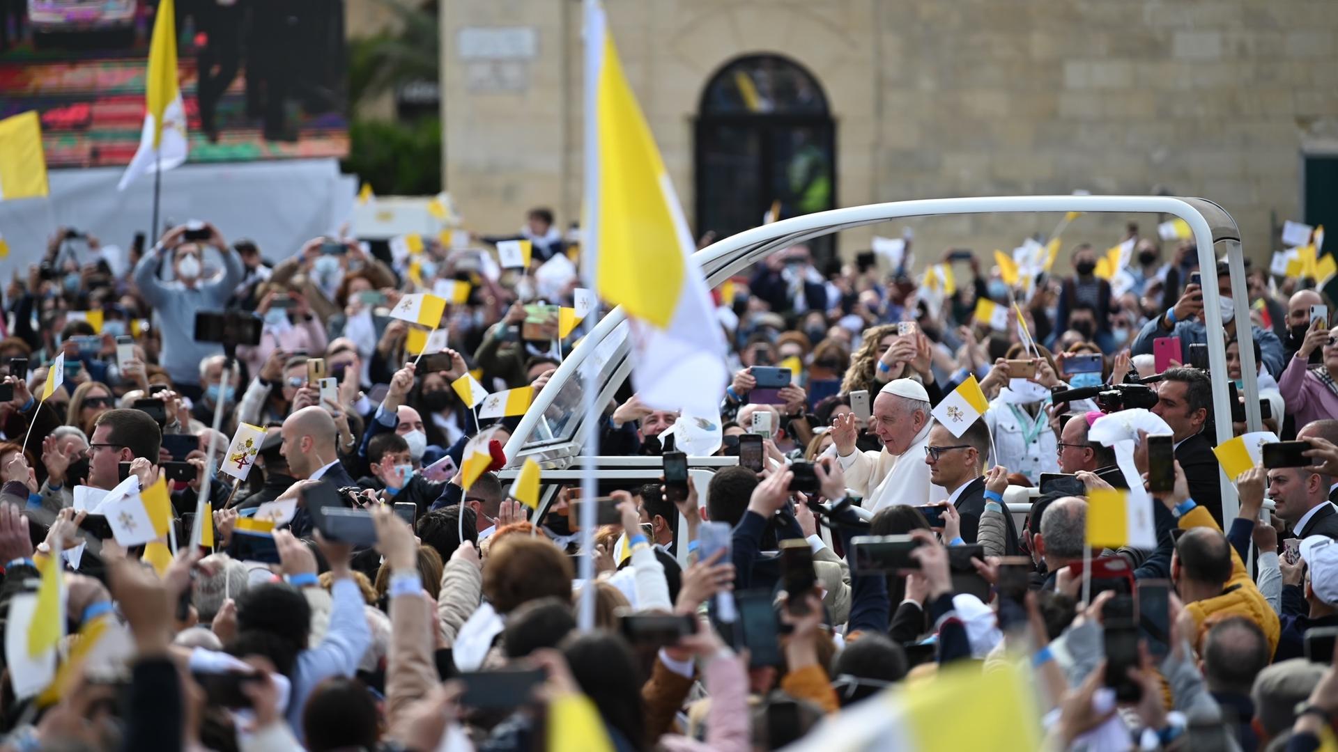 Der Papst im Papamobil, umringt von hunderten Menschen.