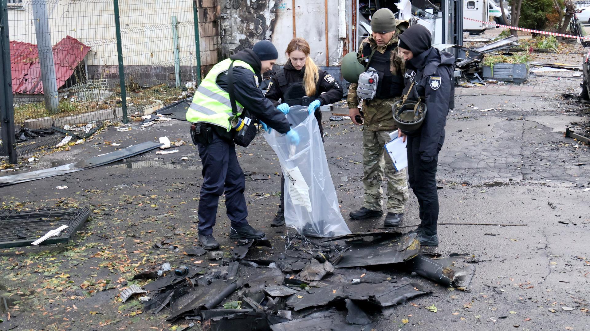 Ordnungskräfte in der ukrainischen Hauptstadt Kiew heben nach einem russischen Angriff die Bruchstücke einer Drohne auf. 