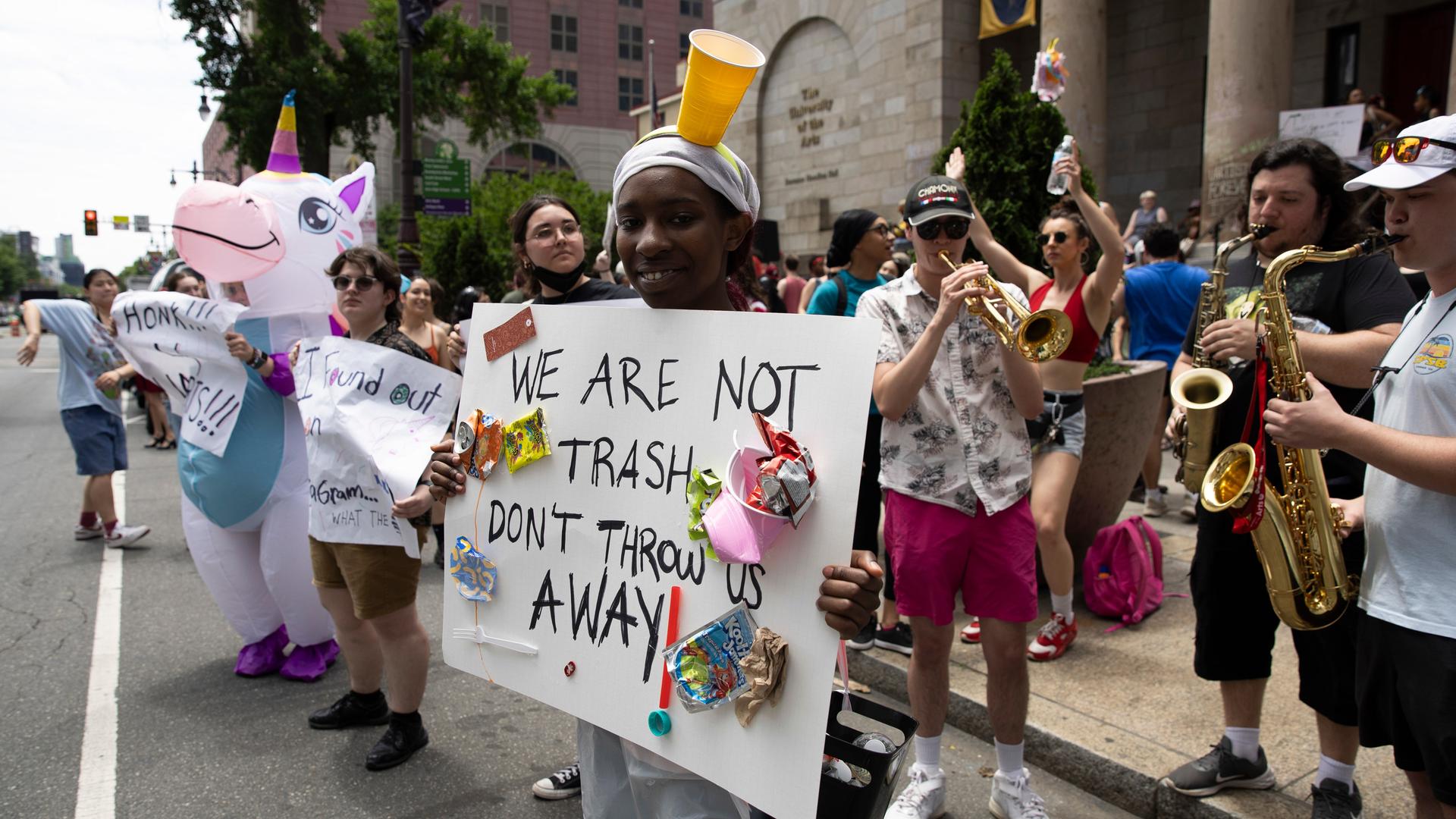 Studierende der University of the Arts in Philadelphia protestieren in Kostümen und mit Instrumenten, auf einem Plakat steht "We are not trash, don´t throw us away" - "Wir sind kein Müll, werft uns nicht weg"