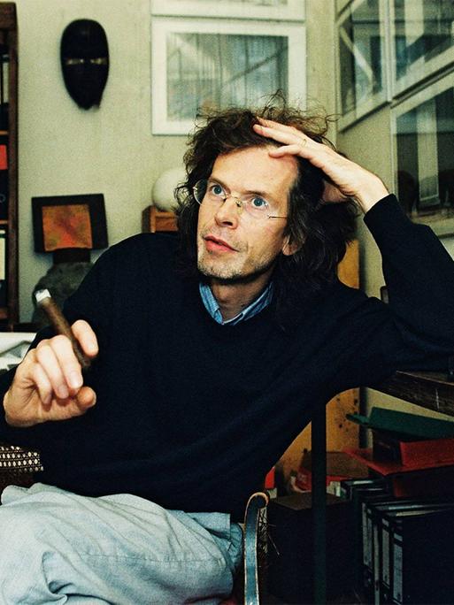 Florian Havemann sitzt mit einer Zigarre an einem Schreibtisch in einer Wohnung voller Bücherregale Florian Havemann sitzt mit einer Zigarre an einem Schreibtisch in einer Wohnung voller Bücherregale