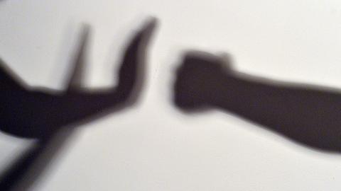 Gestelltes Bild zum Thema häusliche Gewalt - Schatten symbolisieren, wie eine Person sich vor der Gewalt einer anderen schützt.