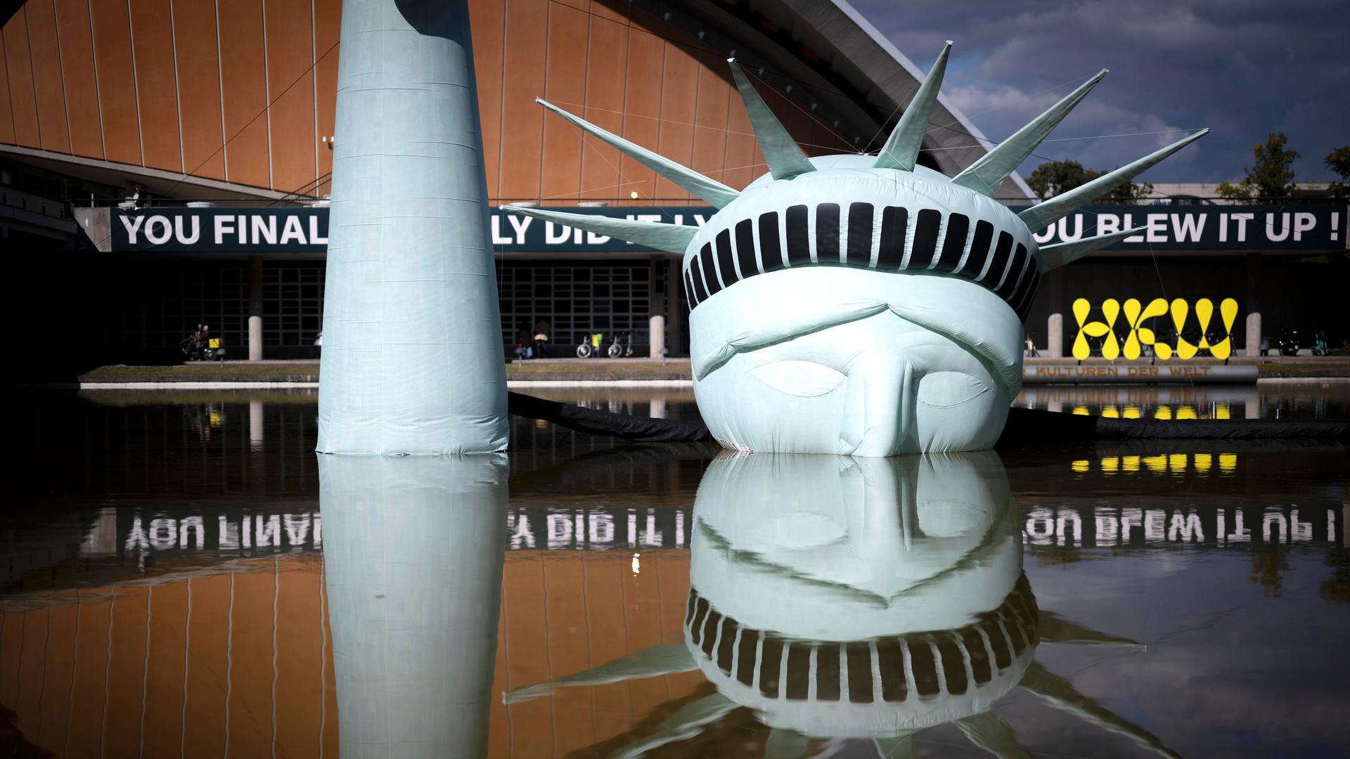 Eine halb versunkene, aufblasbare Replik der Freiheitsstatue liegt im Wasserbecken vor dem Haus der Kulturen der Welt in Berlin. 

