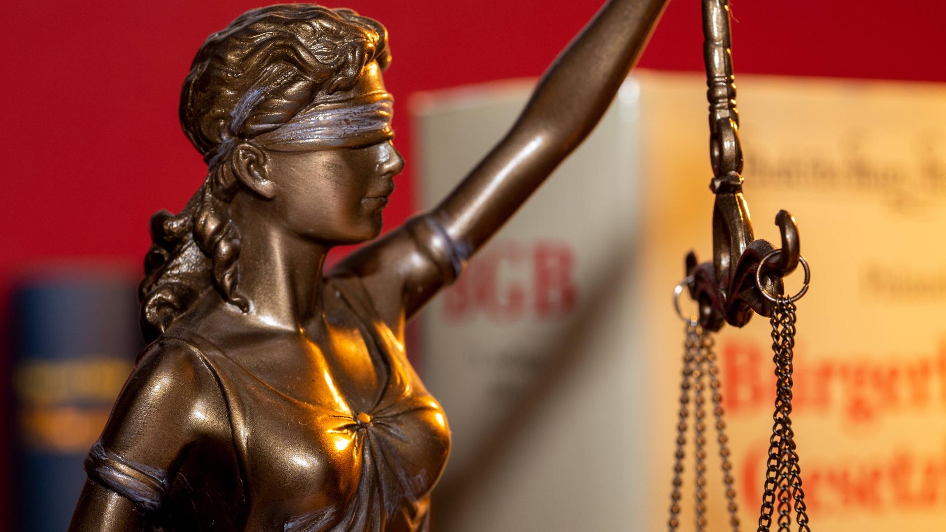 Justitia mit dem BGB Bürgerliches Gesetzbuch im Hintergrund 