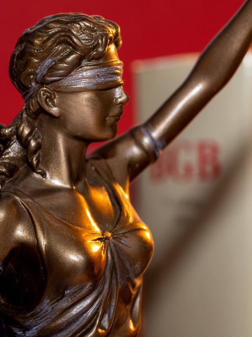 Justitia mit dem BGB Bürgerliches Gesetzbuch im Hintergrund 