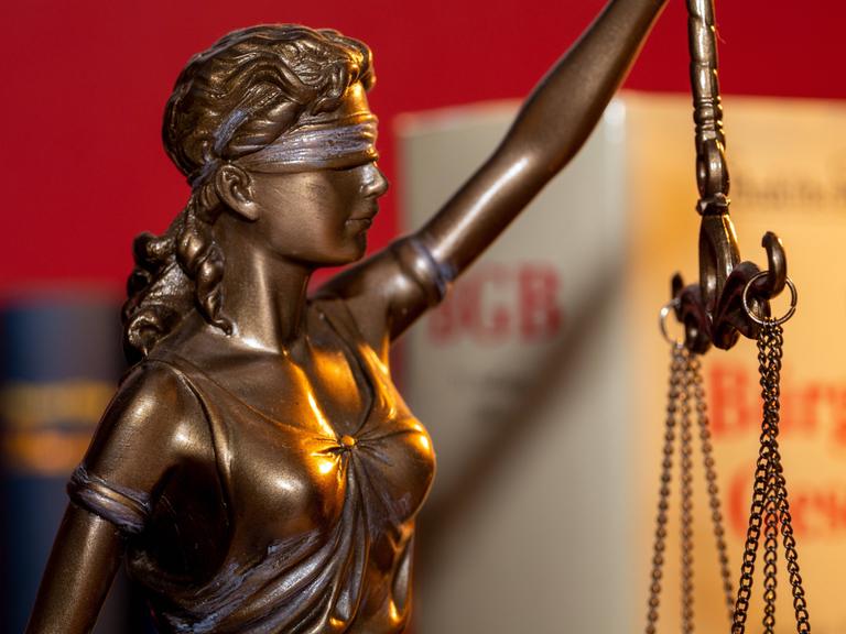 Justitia mit dem BGB Bürgerliches Gesetzbuch im Hintergrund 