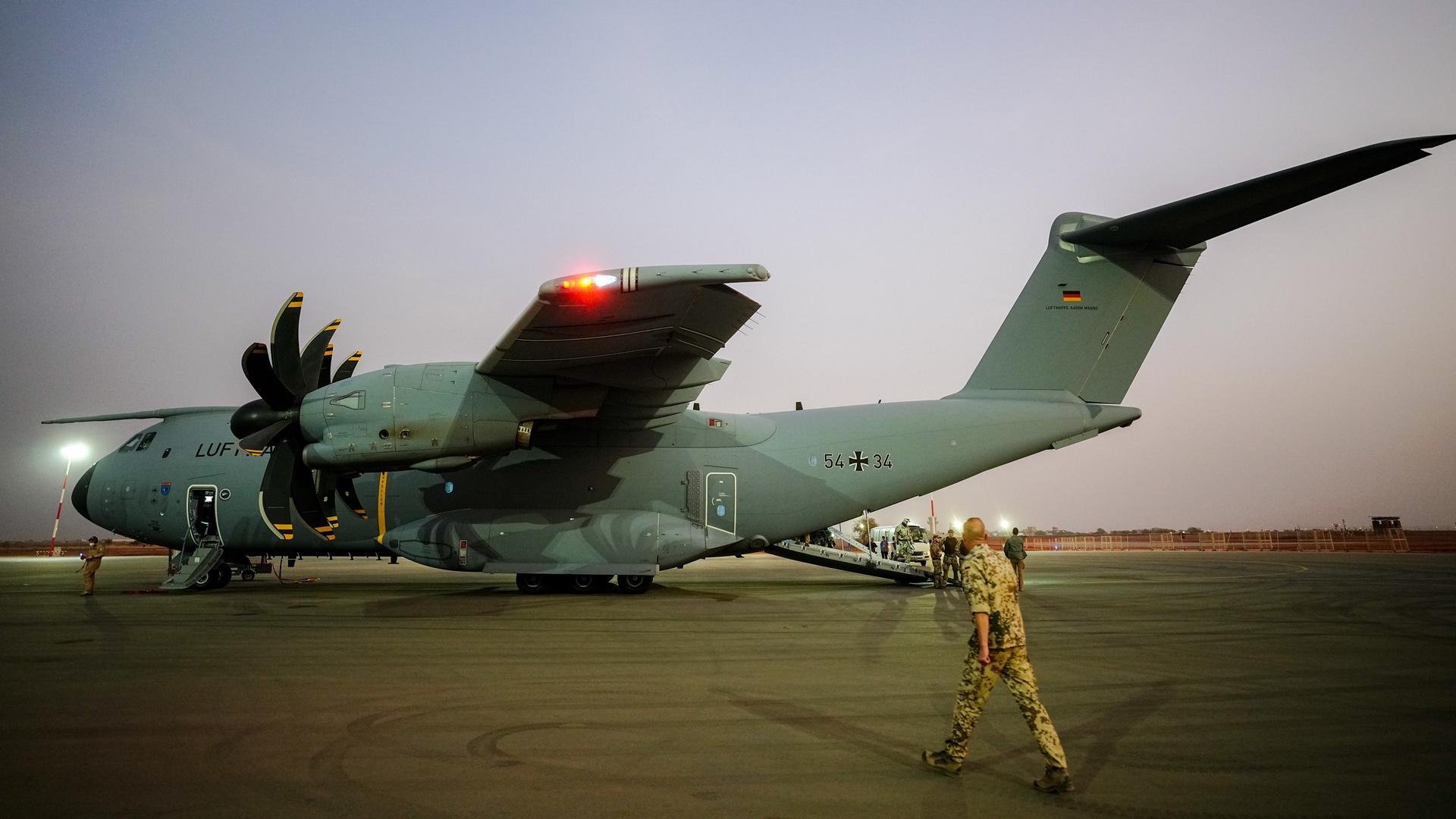 Ein Airbus A400M in der Lackierung der Luftwaffe steht bei Abendlicht auf einem Rollfeld; ein Soldat in khaki-farbener Camouflage läuft auf das Flugzeug zu. Aufnahme vom 09.04.2022. 