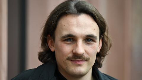 Der Autor Kaleb Erdmann schaut freundlich, mit dunklen Haaren und Schnurrbart. 