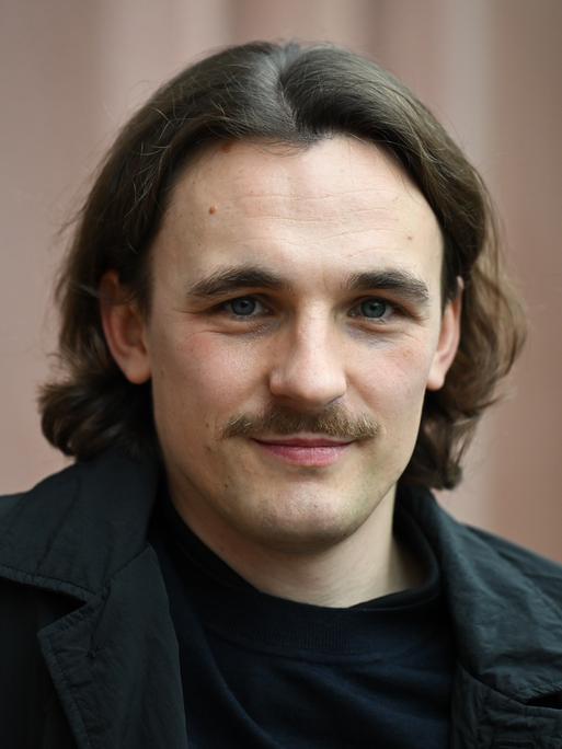 Der Autor Kaleb Erdmann schaut freundlich, mit dunklen Haaren und Schnurrbart. Der Autor Kaleb Erdmann schaut freundlich, mit dunklen Haaren und Schnurrbart.